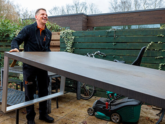 Lachende medewerker Koops met tafel in zijn hand
